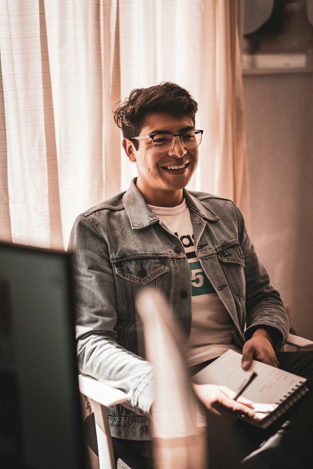 Brazilian man writing personal development notes beside a laptop